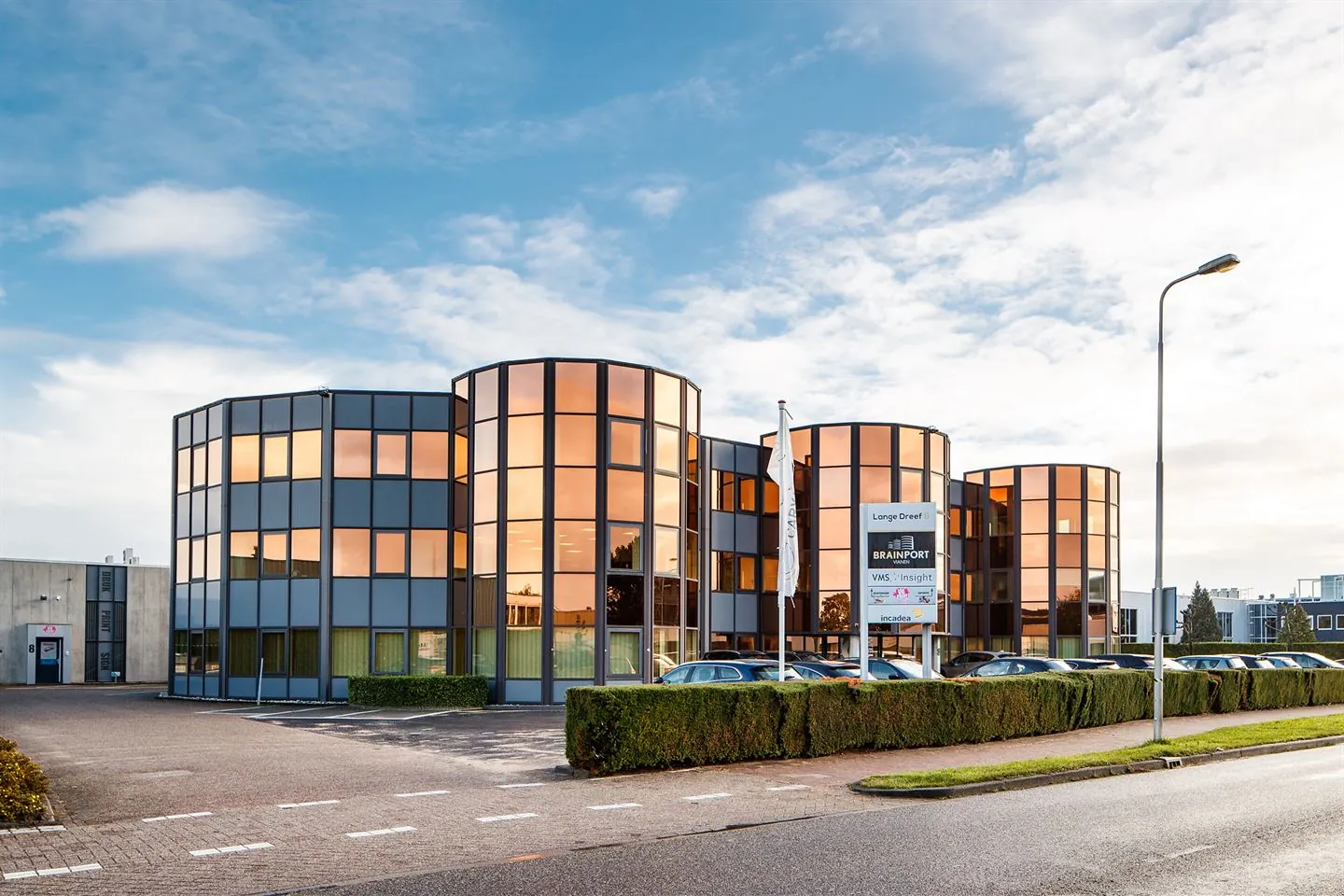Modern kantoorgebouw aan de Lange Dreef met spiegelende ramen en meerdere bedrijfspanden zichtbaar op het naambord.
